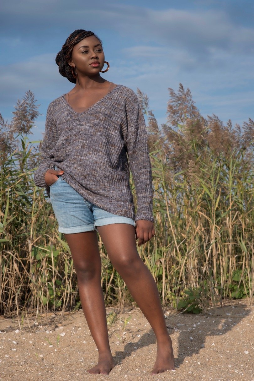 Woman on a beach wearing a loosely-fitting gray textured drop shoulder pullover